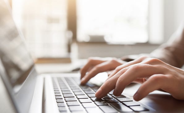 Hands typing on a laptop keyboard.