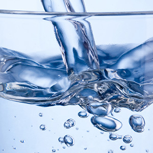 Close up image of water poured into a glass.